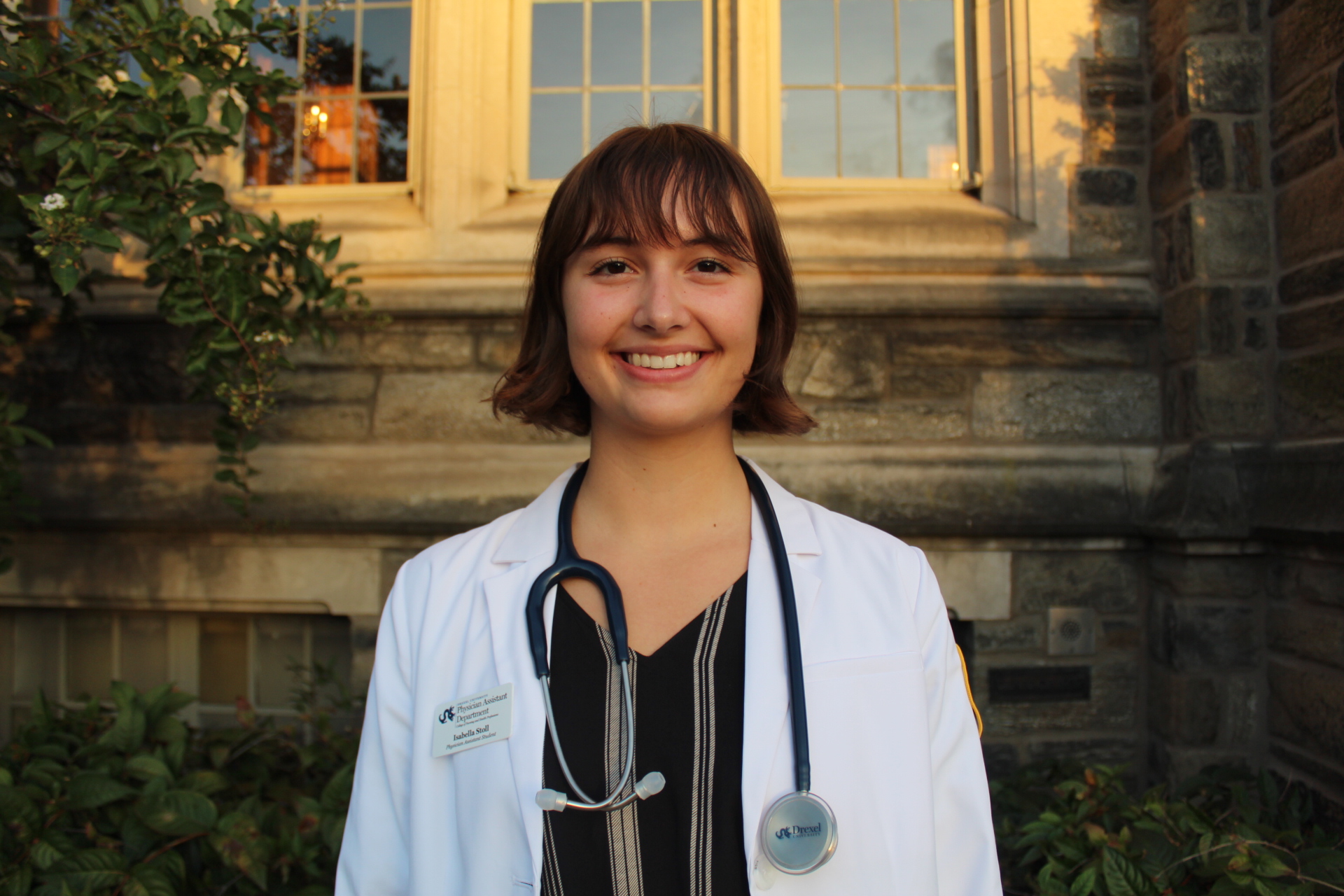 Isabella Stoll wearing white coat with stethoscope around neck